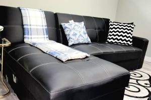 里贾纳QUIET & COZY MODERN SUITE CLOSE TO RCMP的一张黑色皮沙发,上面有枕头