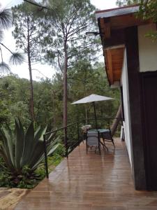 马萨米特拉Mazamitla Pinos del Rio的一个带桌子和遮阳伞的房屋阳台