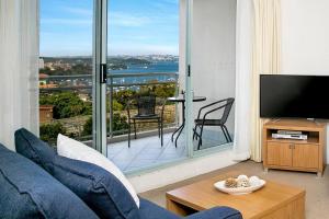 悉尼ALF49-Huge 2BR Penthouse Style, Great Water Views的客厅设有蓝色的沙发和大窗户