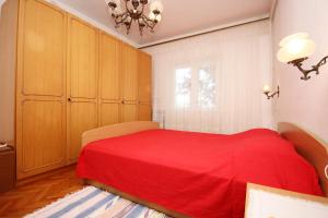 维甘Apartment Viganj 633c的一间卧室配有一张红色的床和木制橱柜。