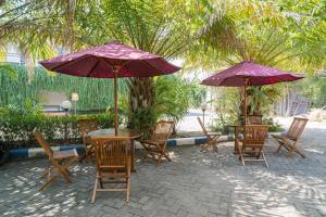 BojonegoroRedDoorz Plus Syariah At Lotus Hotel Bojonegoro的一组桌子和椅子,配有紫色雨伞
