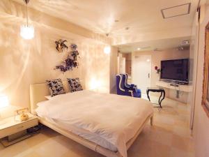 神户V酒店（仅限成人）的卧室配有一张白色大床和电视。