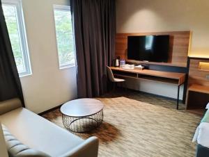 新山NB HOTEL的酒店客房设有一张沙发和一张带电视的书桌。