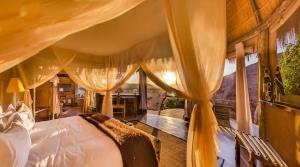 TwyfelfonteinCamp Kipwe的一间卧室配有一张带窗帘的床和一张书桌