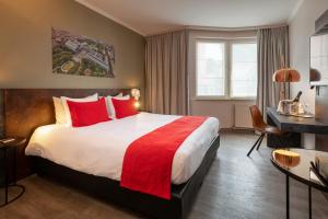 布鲁塞尔马丁布鲁塞尔欧盟酒店的酒店客房配有一张带红色枕头的大床