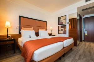 卡萨诺韦Crowne Plaza Milan - Malpensa Airport, an IHG Hotel的一间卧室配有一张带橙色毯子的大床