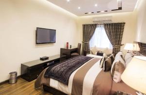 拉合尔Royaute Luxury Suites and Hotel Gulberg Lahore的一间卧室配有一张大床和电视
