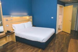 卡萨诺韦米兰马尔彭萨快捷假日酒店的一间卧室设有一张蓝色墙壁的大床