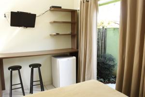 乌巴图巴太阳套房旅馆的一间卧室设有两个酒吧凳、一台电视和一个窗口。