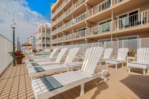 大洋城Comfort Inn Ocean City Boardwalk的坐在建筑物旁边的甲板上的一排白色椅子