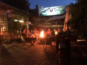 柏林Sandino Hostel - Solo Traveler Sanctuary的一群人晚上坐在火炉旁