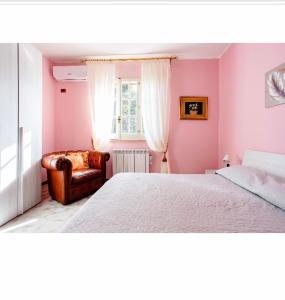 奥古斯塔Villa Angela的卧室设有粉红色的墙壁、一张床和椅子