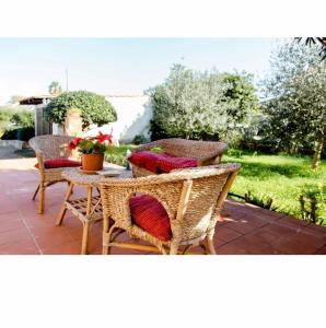 奥古斯塔Villa Angela的庭院设有藤椅和带红色枕头的桌子。