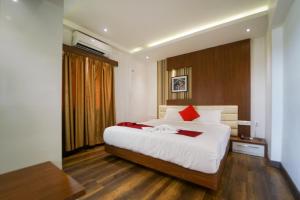 科泽科德Emarald Hotel Calicut的一间卧室配有一张大床,配有白色床单和红色枕头