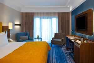 伊斯坦布尔Mövenpick Hotel Istanbul Asia Airport的酒店客房配有床、椅子和电视。