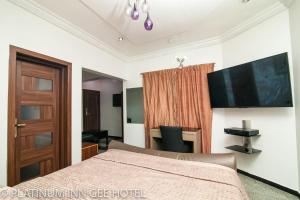 Suru LerePlatinum Inn Gee Hotel的一间卧室配有一张床和一台平面电视