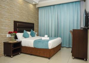 彼得马里茨堡Bayside Hotel Pietermaritzburg的一间卧室配有一张带蓝色窗帘的床和电视。
