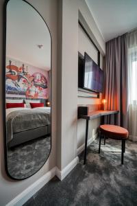 汉诺威NYCE Hotel Hannover的一间带镜子、一张床和一张书桌的卧室