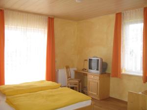 TraisenZur Rotenfelsstube的一间卧室配有一张床和一张书桌上的电视