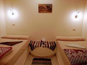 Qasr Al FarafirahRahala Safari Hotel的一间设有两张床的房间和墙上的两盏灯