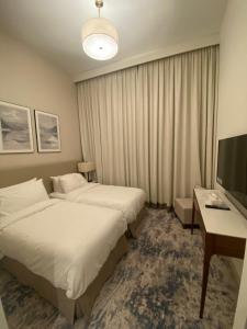 富查伊拉Two Bedroom Apartment Address Residence - Fujairah的酒店客房设有两张床、一张桌子和一台电视。