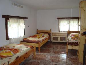 KozhariKuma Lissa Guest House的一间卧室配有两张床、一张桌子和两个窗户。