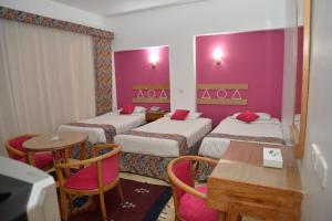 阿斯旺马哈吧宫酒店的酒店客房,设有三张床和一张桌子及椅子