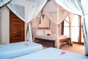 基济姆卡济Zanzibar Kusini Beach Bungalows Hotel的白色窗帘间内的两张床