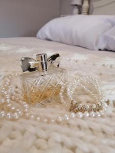 霍维克Cooper Cottage的床上的玻璃香水瓶和珍珠项链