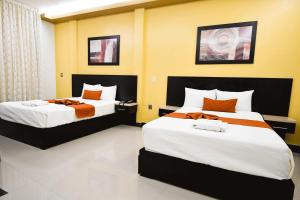 OcozocuautlaHotel los faroles的一间卧室配有两张带橙色和白色床单的床