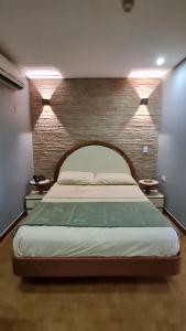 加拉加斯Hotel El Arroyo的一间卧室设有一张带砖墙的大床