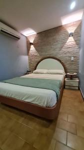 加拉加斯Hotel El Arroyo的一间卧室设有一张带砖墙的大床