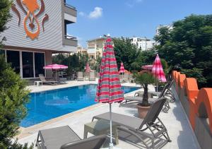 安塔利亚Lara Olympos Hotel的一座带椅子和遮阳伞的游泳池位于一座建筑旁边