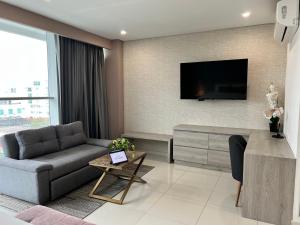 蒙特里亚Hotel Sexta Avenida Inn的客厅配有沙发和墙上的电视