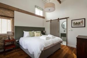 斯坦福德Linseed Barn- Stamford Holiday Cottages的一间卧室配有一张带白色床单的大床