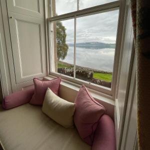 因弗内斯班奇鲁别墅酒店的窗户配有粉色和白色的枕头,沙发
