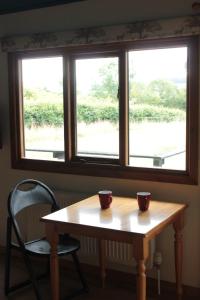 阿什伯恩Couples Camping Cabin的窗前木桌上的两杯