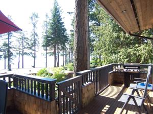 鲍威尔里弗Malaspina Strait Cottage的木甲板上种有树,配有桌椅