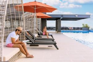 普拉亚卡门Singular Dream Beach Residences的坐在游泳池旁长凳上的男人
