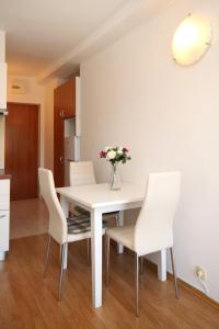 斯拉诺Apartment Slano 2682c的白色的餐桌,配有白色的椅子和花瓶