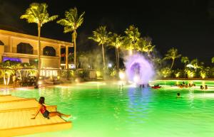 塞班Coral Ocean Resort的度假村的游泳池,晚上有喷泉