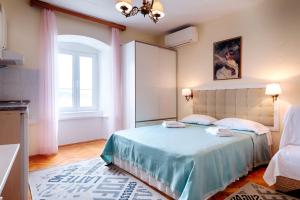 科米扎Apartments and rooms by the sea Komiza, Vis - 2431的一间卧室配有一张带蓝色床单的床和一扇窗户。
