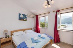 斯拉诺Apartments and rooms by the sea Slano, Dubrovnik - 2687的一间卧室配有一张带红色窗帘的床和一扇窗户