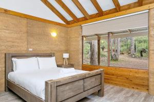 邓斯伯勒Possum Cottage - Woodstone Estate的一间卧室设有一张床和一个大窗户