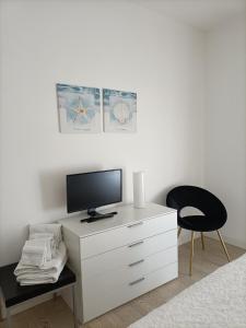 利多迪耶索罗CASA Chloe'的卧室配有带电视和椅子的白色梳妆台。