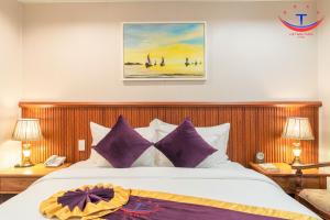 归仁Vietnam Taste Hotel Quy Nhon - Beachfront的一间卧室配有一张带紫色枕头的大床