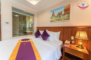 归仁Vietnam Taste Hotel Quy Nhon - Beachfront的配有一张大床和一部电话的酒店客房