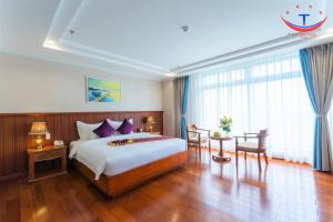 归仁Vietnam Taste Hotel Quy Nhon - Beachfront的一间卧室配有一张大床和一张桌子及椅子