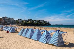迪纳尔Dinard: studio à 100 m de la plage de L'Ecluse的海滩上的蓝白遮阳伞