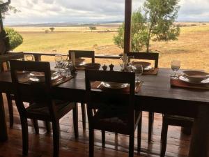 TimauChui Cottage with tennis facing Mt Kenya & near Ngare Ndare的一张木桌,配有椅子和盘子,酒杯